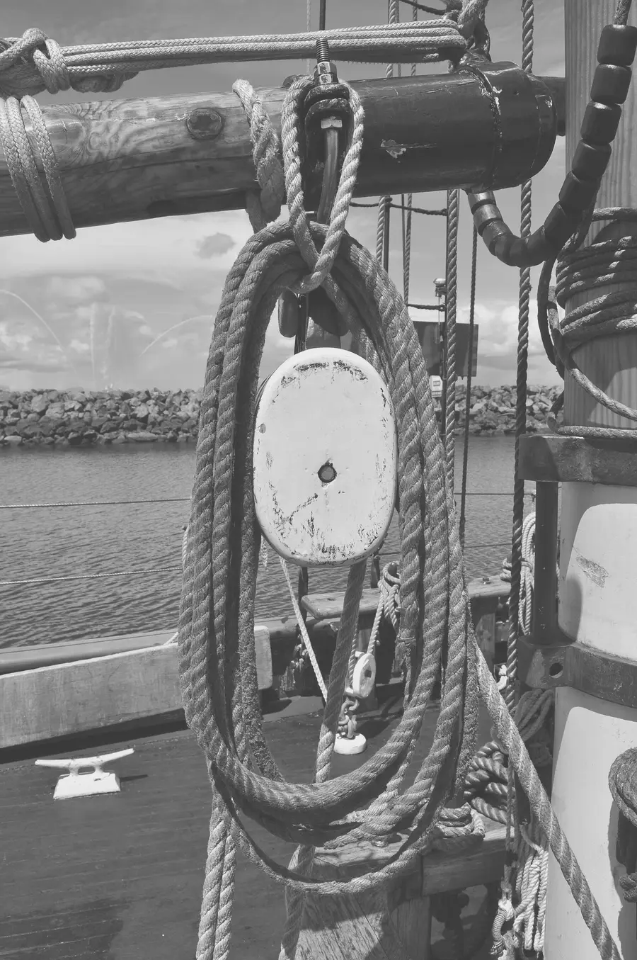 A wooden block with its sheave, hung from a boom with coiled rope through it.